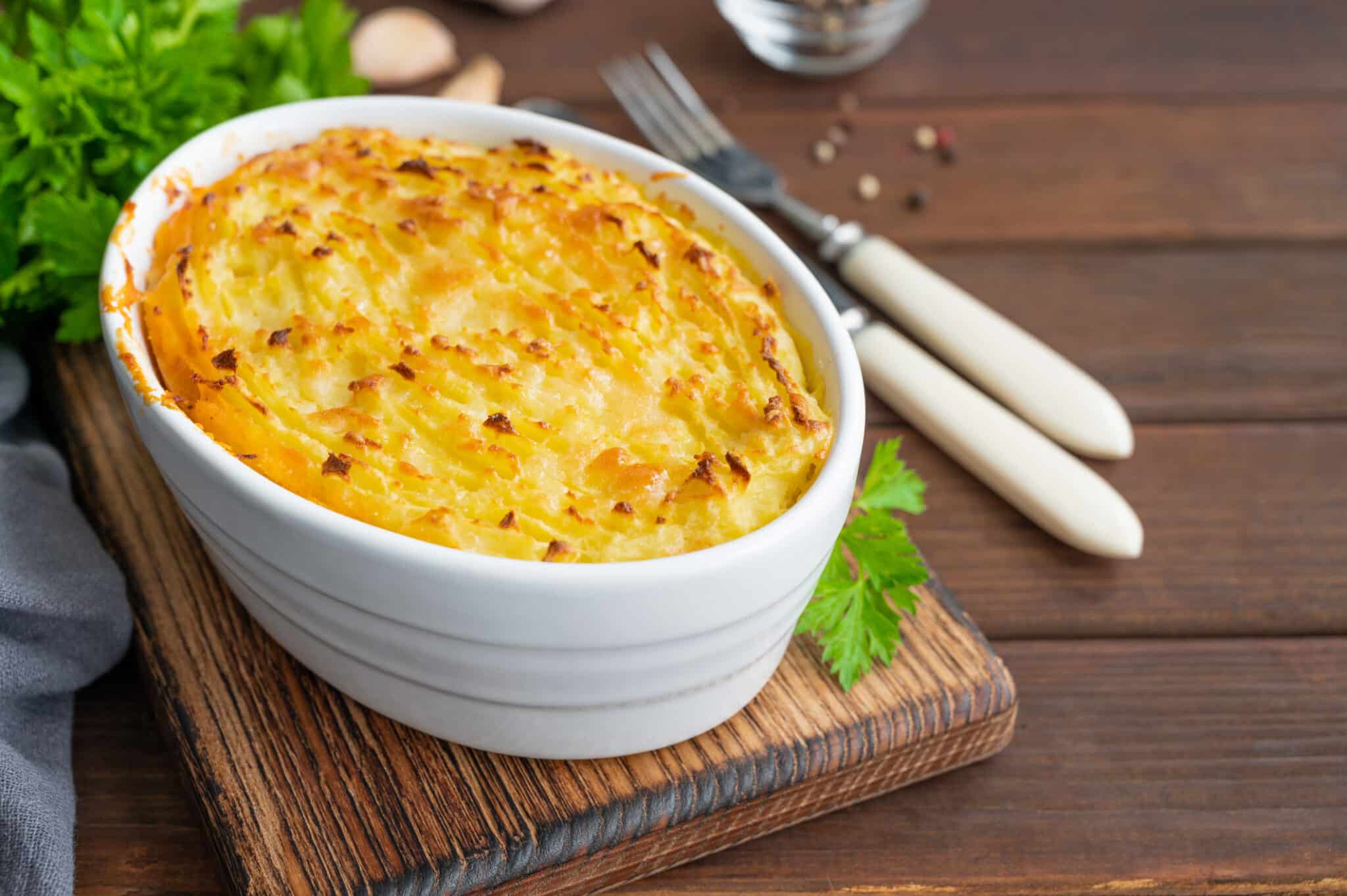 Homemade Shepherd's Pie in the casserole dish on a dark wooden background. Traditional British dish with minced meat and mashed potatoes